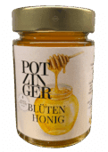 Ein 250g-Glas Blütenhonig mit einem goldenen Deckel. Das Etikett zeigt einen Honiglöffel, der Honig in ein Glas träufelt, und einen deutschen Text.